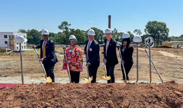 A group of 5 people holding shovels to break ground.