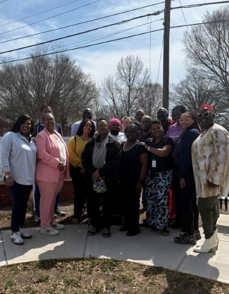 A group of people standing on a sidewalk smiling for a picture.