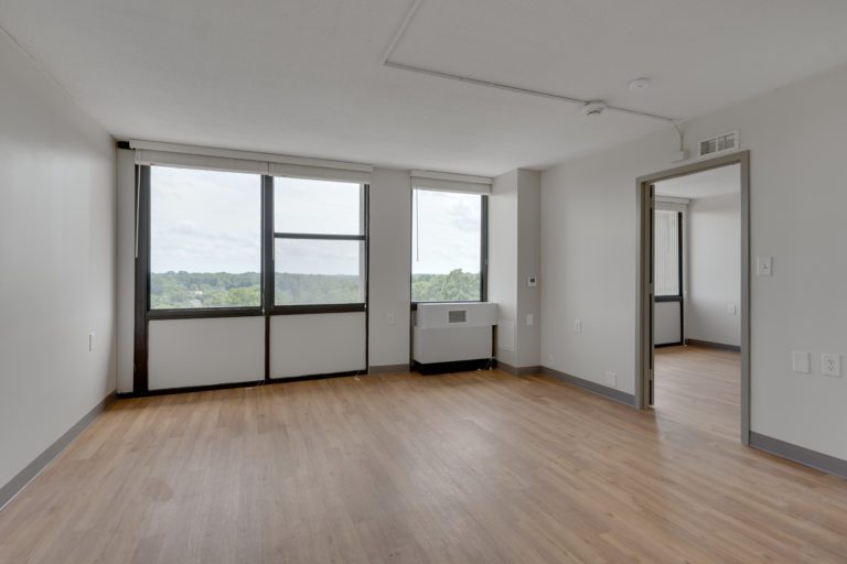 One of the living rooms at JJ Henderson featuring wooden floors and several windows.