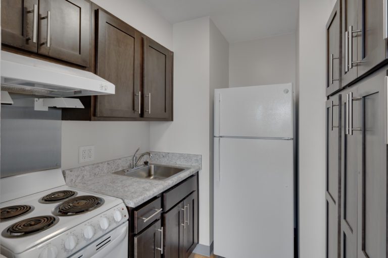 A kitchen with brown wooden cabinets and white appliances.