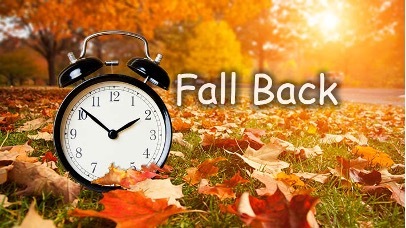 Fall Back. A clock on a leaf covered lawn.