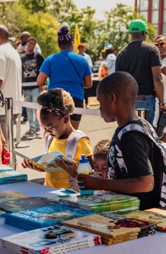Children standing around a table reading books on display.