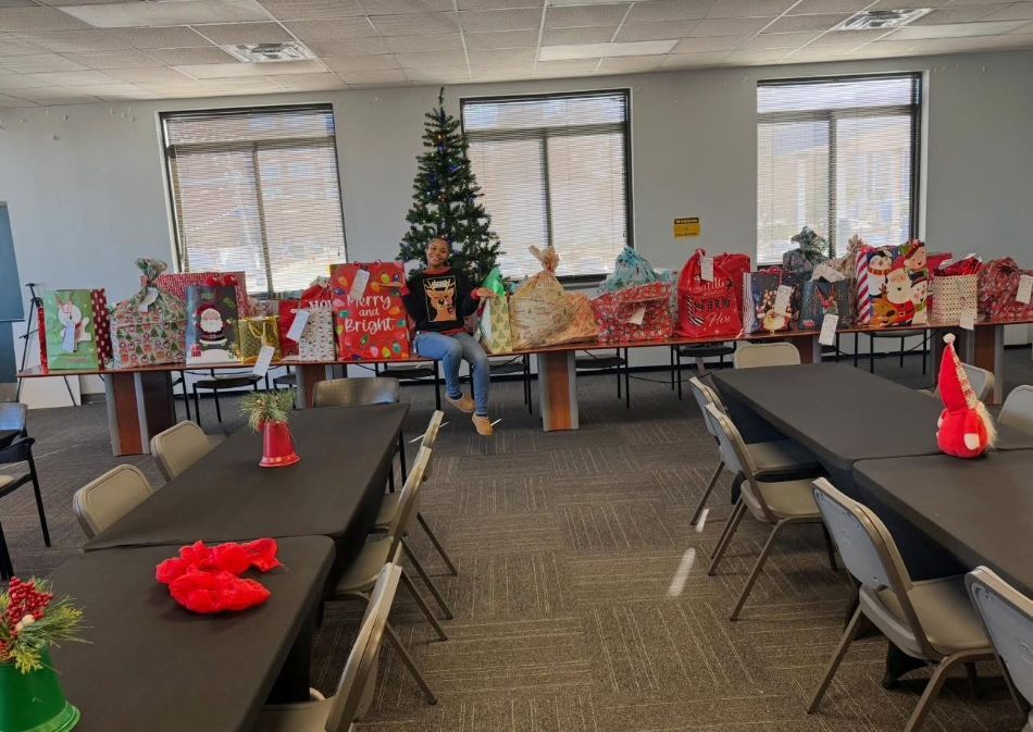 A woman sitting and smiling on a table full of presents.