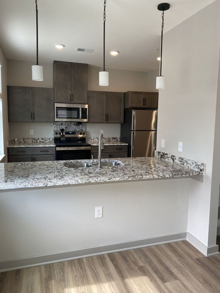 A view of a kitchen with granite countertops.