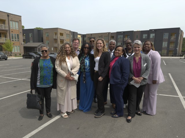 A group of individuals posing for a group photo in a parking lot.