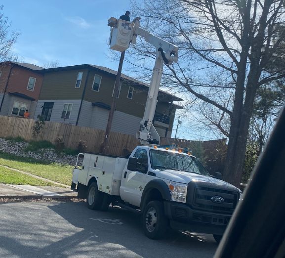 A bucket truck with an individual lifted up to work at the top of a pole.