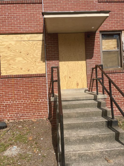 A set of stairs leading up to a boarded up door and windows.