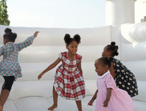 Four children jumping on a bouncy house.