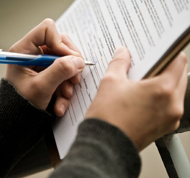 A close-up of someone filling out a form on a clipboard.
