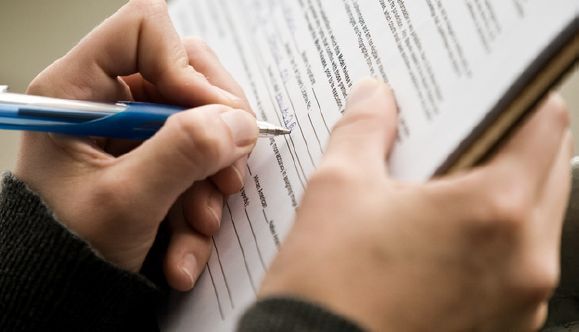 A close-up of someone filling out a form on a clipboard.