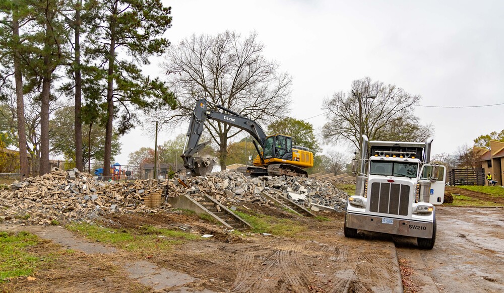 An Excavator picking up materials with a truck next to it