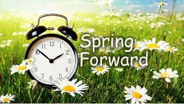 Spring Forward. Clock sitting in a grassy field of daisies.