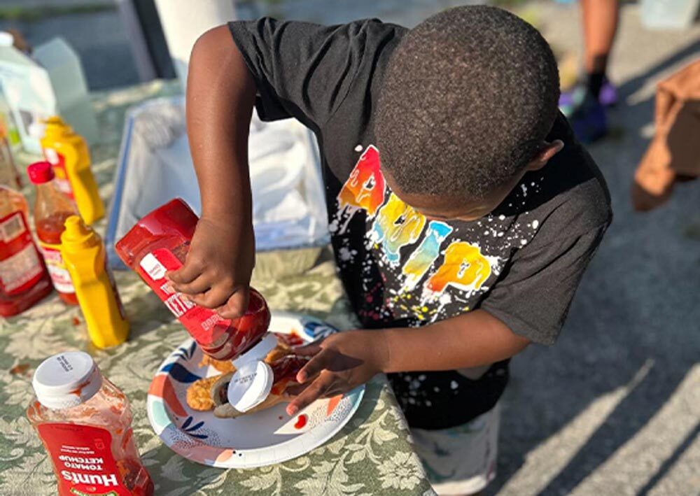 A boy pouring ketchup on his plate.