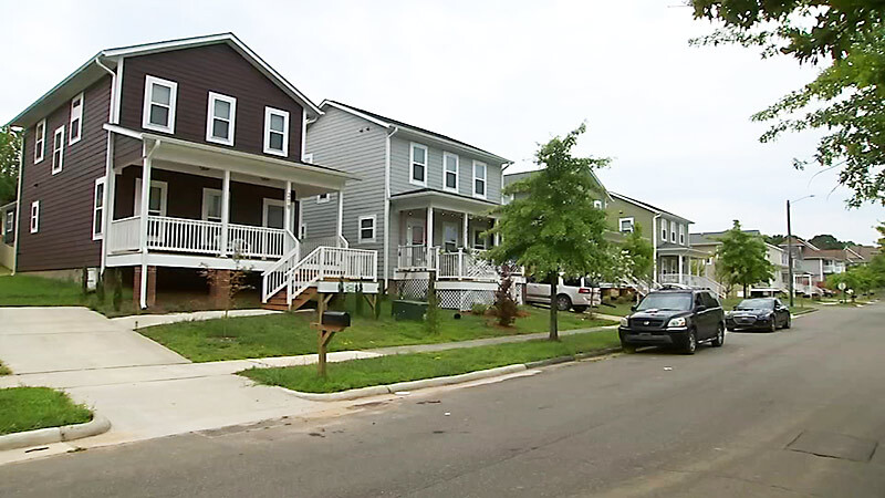 row of 2 story homes  with front porches and cars parked on street