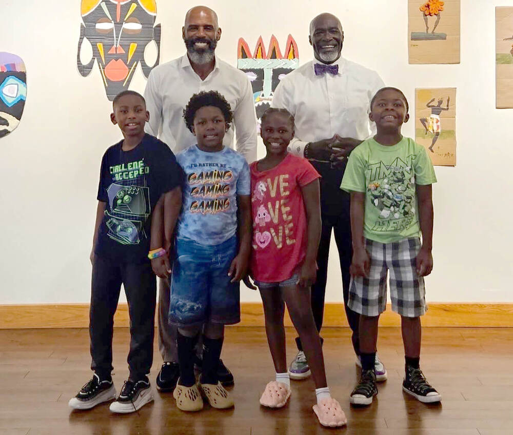 Two adults and four children smiling for the camera as participants of the Art Exhibit