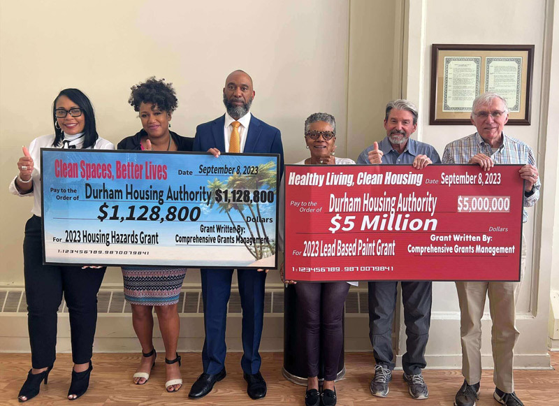 Durham Housing Authority staff holding two large grant checks.