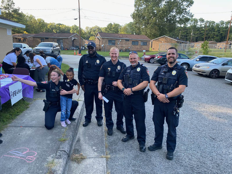 Police officers standing with a little girl.