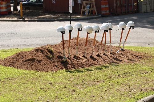 10 shovels with hardhats on shovel handles in pile of dirt