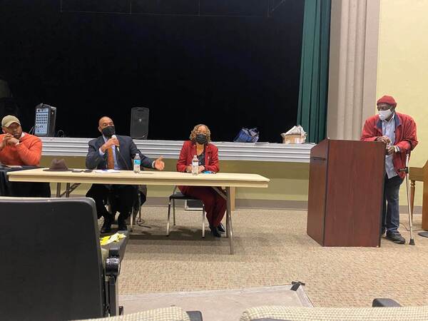 Person speaking into microphone sitting at a table