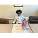 a boy sitting at a desk with an award and a gift bag