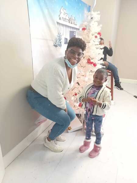 A woman and a child standing by a Christmas tree