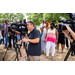 A crowd of people has gathered behind the line of camera men who are filming the speakers.