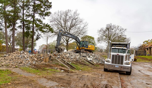 An Excavator digging in the dirt with a truck next to it