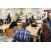 People sitting at desks patiently while listening to the instructor speak.