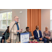 A man speaking at a podium while others are listening.