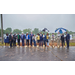 Various individuals standing outside in the rain with umbrellas.