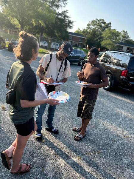 CnS1.jpg A group of individuals standing next to each other holding paper plates.