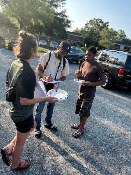 A group of individuals standing next to each other holding paper plates.