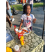 A young girl standing at a table holding a paper plate with food on it.