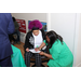 A woman sitting while another woman writes on a document.