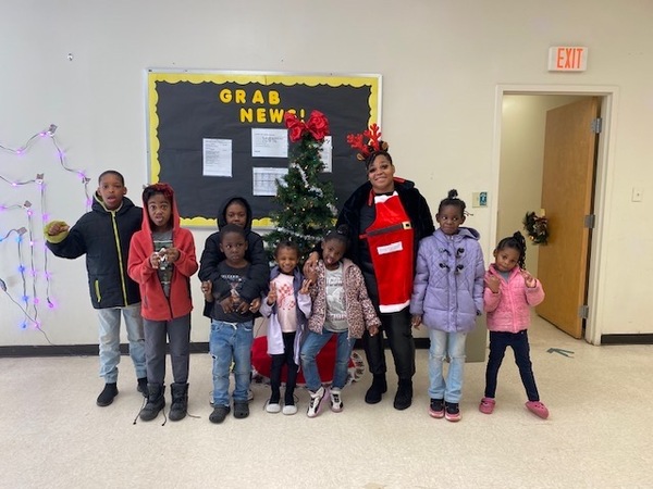 1stphoto.jpg A woman standing next to a group of children in front of a Christmas tree.