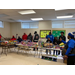 Individuals in a room with presents sitting on a long table.