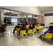 A group of individuals sitting in yellow chairs listening to the speaker.