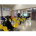 Individuals listening to a presentation while sitting in yellow chairs.