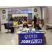 Two woman sitting at a table with a sign that reads: DHA, Durham Housing Authority Jobs Plus.