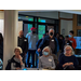 A large group of people watching a presentation while standing by the entrance.