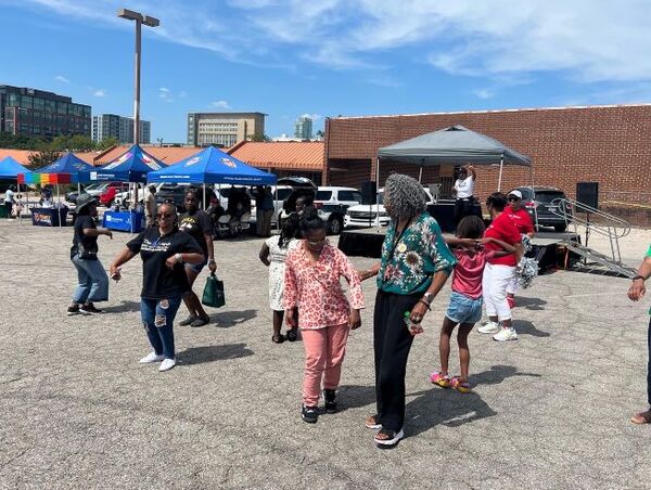 DUHANCBlockParty1.jpg A group of individuals walking around the parking lot with blue pop up canopies in the background.