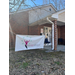 A brick building with a In Her Vision banner hanging in the front.