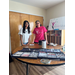Two women standing behind a table lined up with various types of glasses frames.