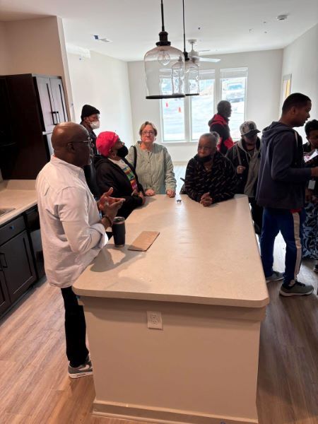 CNITour1.jpg A group of people standing and talking around a kitchen island.