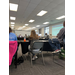  The backs of individuals sitting around tables while listening to a speaker. 