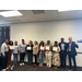  Eleven people standing in a line against a wall for a group photo with the READS Scholarship recipients. 