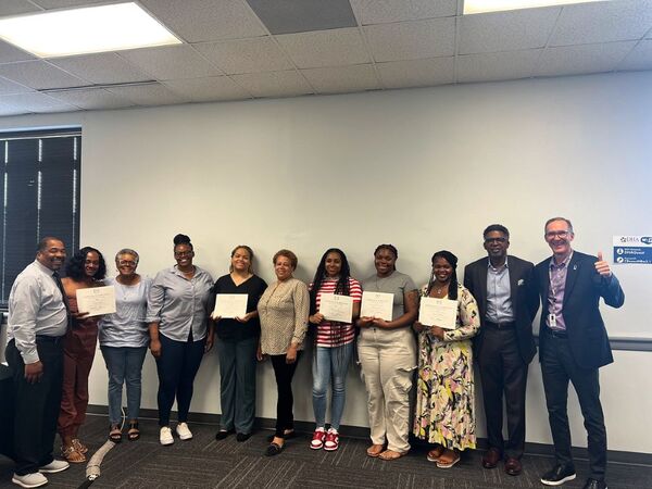 DUHANCREADS2025ScholarshipWinners.png1.jpg Eleven people standing in a line against a wall for a group photo with the READS Scholarship recipients.