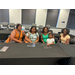  Five women sitting together at a black table. 