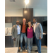  Four people stand and smile for a picture in the kitchen of the Vanguard Apartments. 