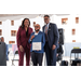  A woman and two men smiling for a photo with an award for the Vanguard Apartments. 